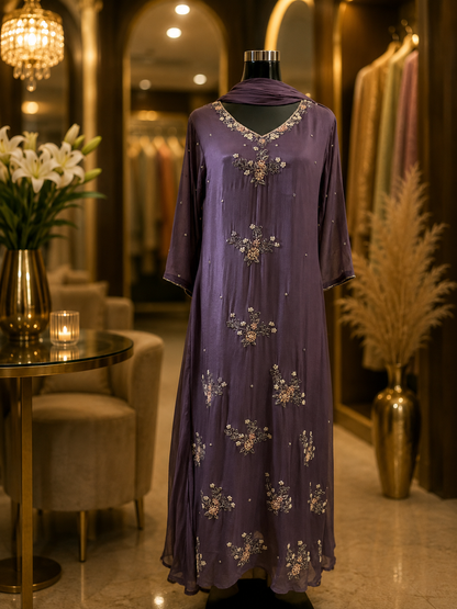 A purple three-quarter sleeve maxi dress with intricate gold and silver embroidery, displayed on a mannequin in a luxury boutique setting.