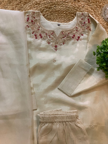 Beige traditional outfit with floral embroidery on a textured surface