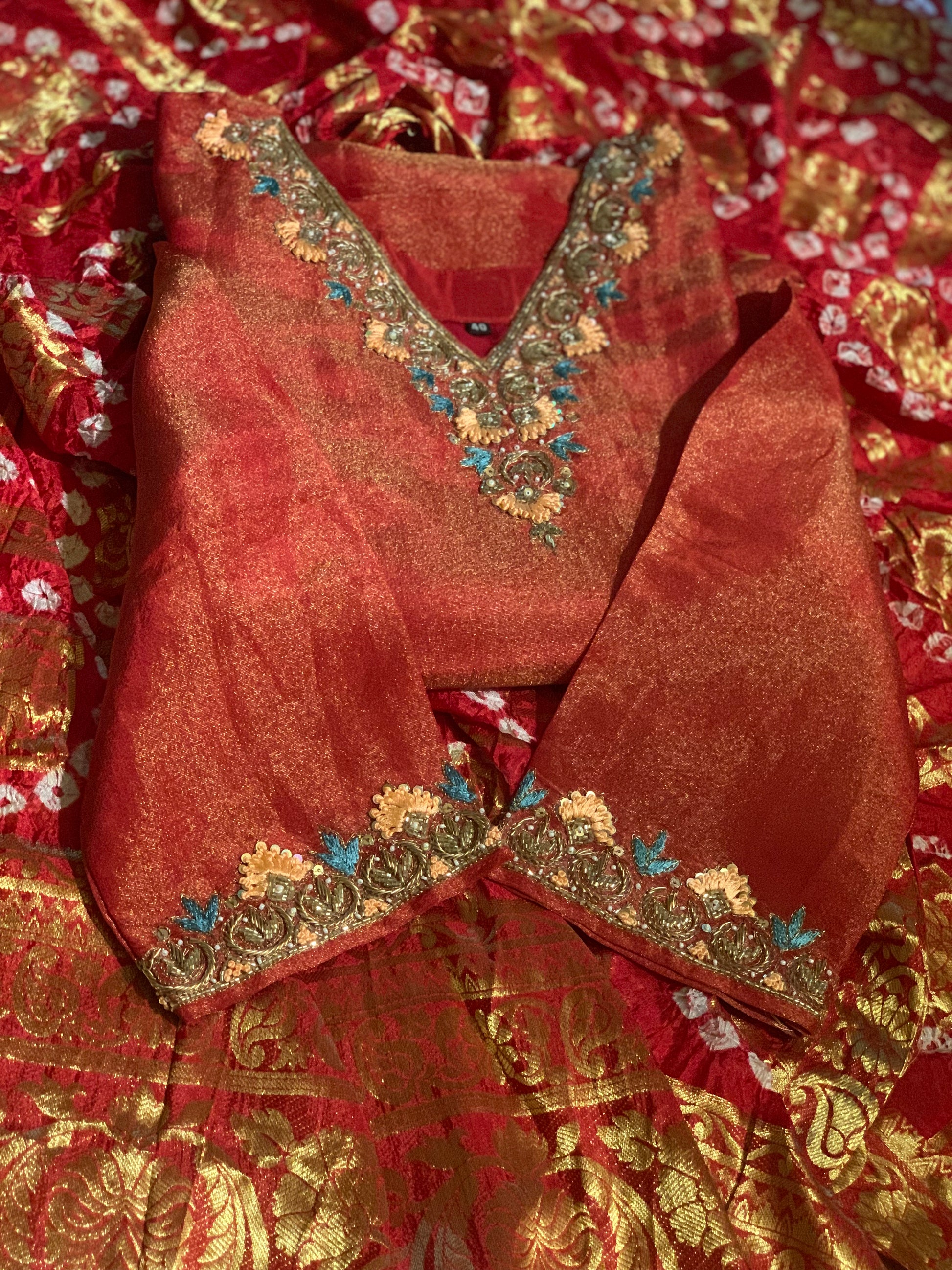 Red traditional outfit with gold embroidery on a matching fabric background