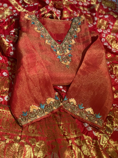 Red traditional outfit with gold embroidery on a matching fabric background