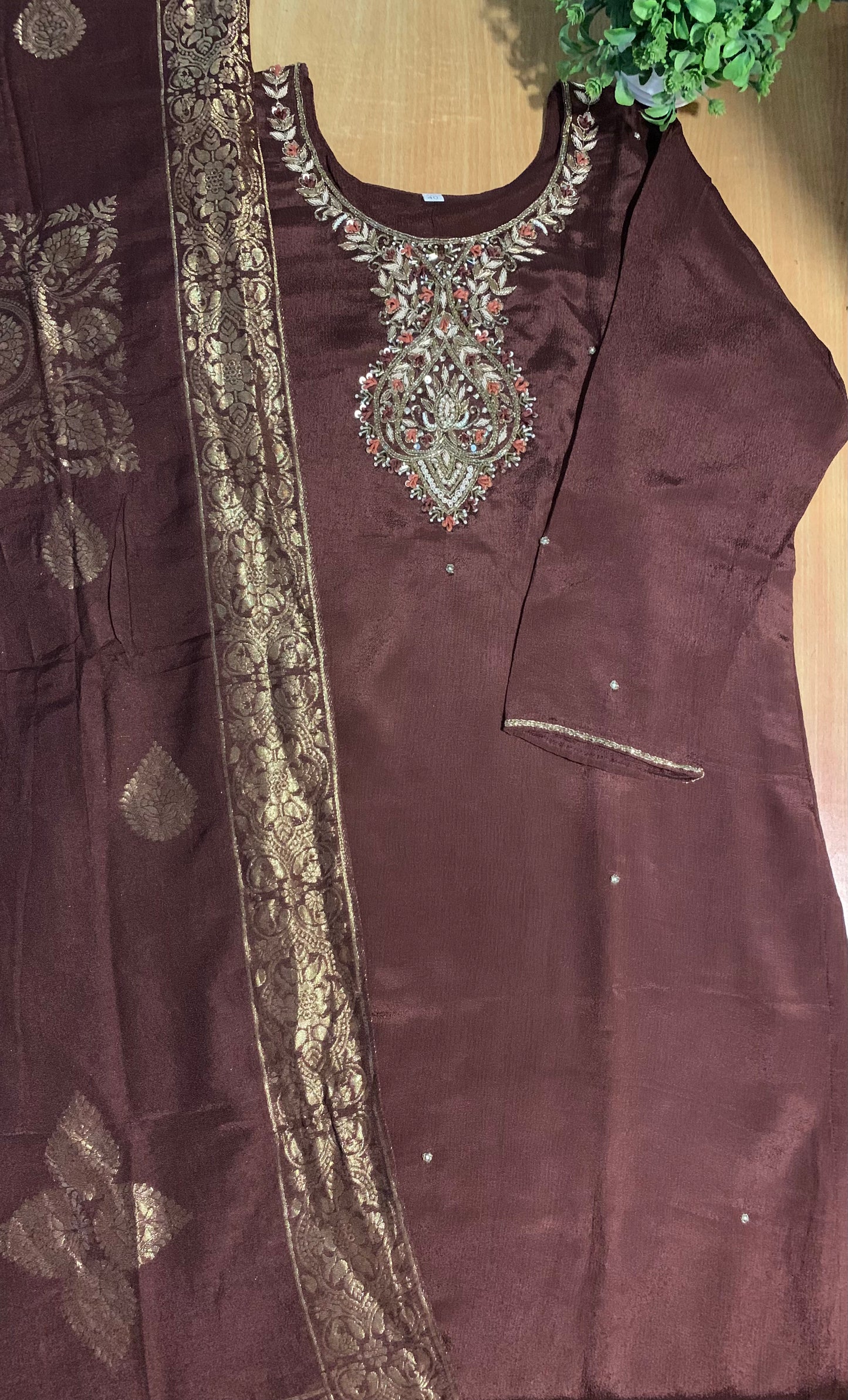 Brown embroidered outfit with intricate patterns on a wooden surface