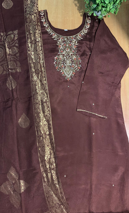 Brown embroidered outfit with intricate patterns on a wooden surface